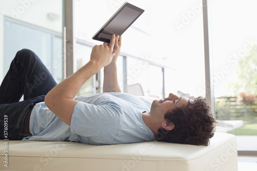 Photo: Man laying down using digital tablet Man laying down using digital tablet