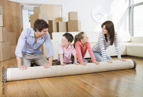 Photo: Family unrolling carpet together in new home Family unrolling carpet together in new home