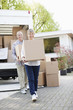 Couple unloading boxes from moving van