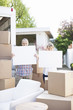 Couple standing near moving van holding blank cards