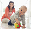 Mother watching baby playing with ball