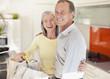 Smiling couple in kitchen with reusable grocery bags