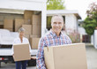 Couple unloading boxes from moving van