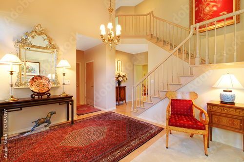 Photo: Luxury entrance living room with red rug, staircase. Luxury entrance living room with red rug, staircase.