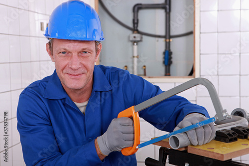 Photo: Plumber sawing length of plastic pipe Plumber sawing length of plastic pipe