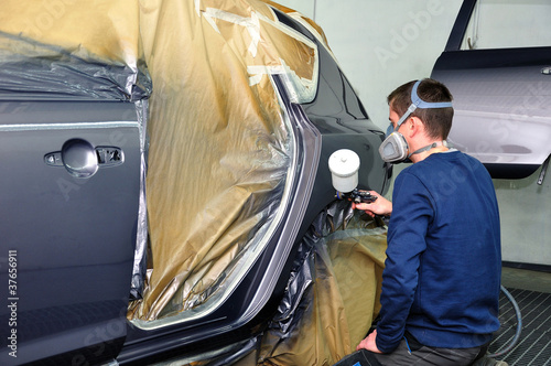 Photo: Worker painting a car. Worker painting a car.