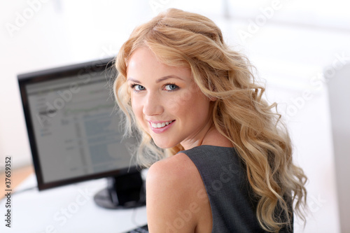 Photo: Portrait of beautiful woman sitting in front of desktop computer Portrait of beautiful woman sitting in front of desktop computer