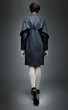 Fashion model brunette in grey coat walking away