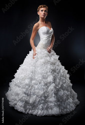 Photo: Pretty bride in white nuptial dress posing in studio Pretty bride in white nuptial dress posing in studio