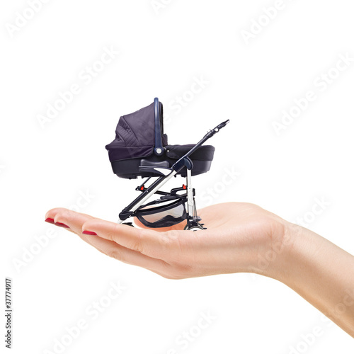 Photo: Beautiful manicured female hand holding a baby carriage Beautiful manicured female hand holding a baby carriage