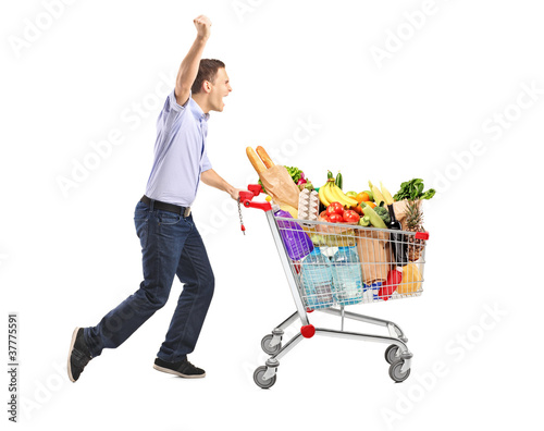 Photo: Euphoric man pushing a shopping cart full with food Euphoric man pushing a shopping cart full with food