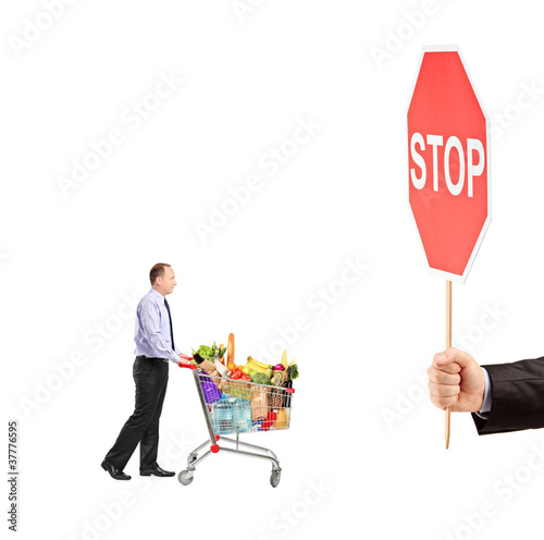 Photo: Man pushing a shopping cart full with food and a hand holding a Man pushing a shopping cart full with food and a hand holding a