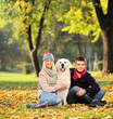 Smiling young man and woman hugging a labrador retreiver dog