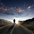 Man walking away at dawn along road