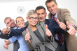 Photo: Business approval - Young colleagues with thumbs up sign Business approval - Young colleagues with thumbs up sign