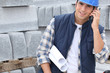 Construction worker with building plans and cellphone