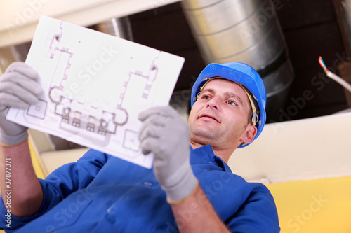 Foto: Man looking at plans for a heating installation Man looking at plans for a heating installation