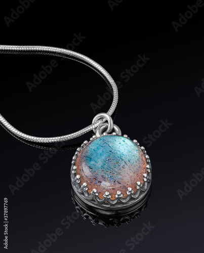Photo: Round silver jewelry pendant on black background. Round silver jewelry pendant on black background.