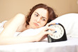 Woman lying a bed and holding an alarm (focus on woman) Woman lying a bed and holding an alarm (focus on woman)