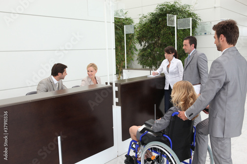 Photo: Businesswoman in a wheelchair with her colleagues at reception Businesswoman in a wheelchair with her colleagues at reception