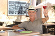 senior man toasting on a cafe terrace