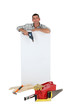 Man holding drill next to blank advertising panel