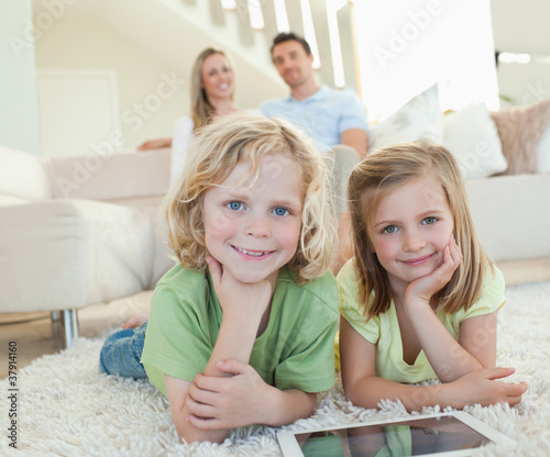 Photo: Children on the carpet with tablet and parents behind them Children on the carpet with tablet and parents behind them