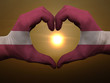Heart and love gesture by hands colored in latvia flag during be
