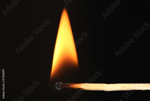 Photo: Burning match on black background Burning match on black background
