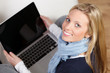 blonde junge frau sitzt mit notebook auf dem sofa