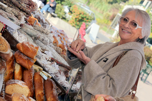 Photo: Woman buying bread from market stall Woman buying bread from market stall