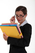 Secretary holding a binder and peering over her glasses
