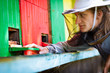 Beekeeper by an apiary observing carefully his bees