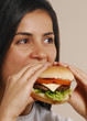 Joven mujer comiendo hamburguesa.