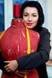 seamstress with red old mannequin and measuring tape in her work