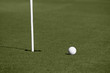 Golf ball close to hole with flagstick on putting green Golf ball close to hole with flagstick on putting green