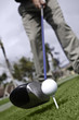 Angled view of golfer addressing golf ball on tee with driver Angled view of golfer addressing golf ball on tee with driver
