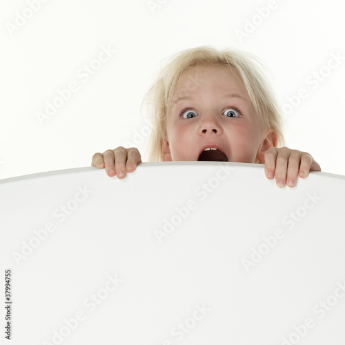 Photo: Little girl crying terrified on a white wall with copyspace Little girl crying terrified on a white wall with copyspace