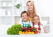 Woman and kids with vegetables in the kitchen Woman and kids with vegetables in the kitchen