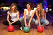 Foto: three girls sit with balls in bowling club and smile three girls sit with balls in bowling club and smile