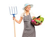 A female farmer holding a pitchfork and basket with vegetables
