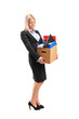 Fired businesswoman in a suit carrying a box of personal items
