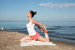 Photo: Young beautiful woman doing yoga near the sea alone Young beautiful woman doing yoga near the sea alone