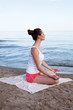 Photo: Young beautiful woman doing yoga near the sea alone Young beautiful woman doing yoga near the sea alone