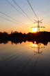 Electricity pylon with reflection in water at sunset