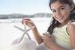 Portrait of smiling girl holding starfish on beach