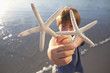 Portrait of boy holding two starfish on beach