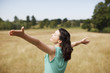 Woman with arms outstretched in sunny rural field