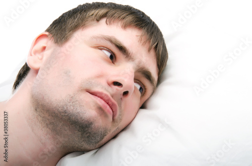 Photo: Man in bed trying to sleep with a pillow Man in bed trying to sleep with a pillow