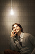 Smiling businessman sitting under illuminated light bulb
